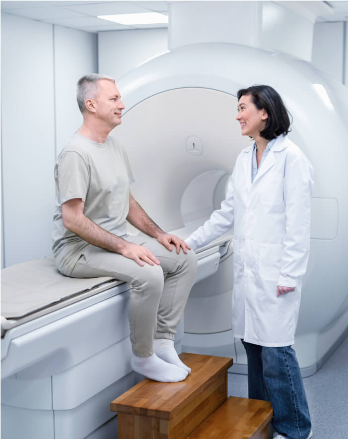 A man and woman seated in front of an MRI machine, undergoing a medical scan.